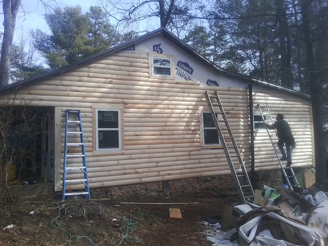 Ladders set against fresh log siding during an exterior remodel in Farmington